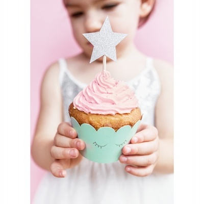 Cupcake com cobertura rosa e topper estrela segurado por criança em fundo rosa