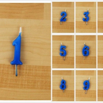 Velas azuis em forma de números sobre madeira clara.
