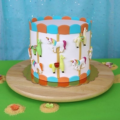 Bolo decorado com unicórnios e lhamas em relevo, base de madeira