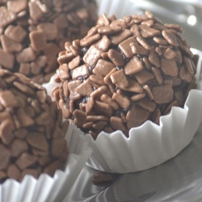 Brigadeiros com granulados de chocolate em forminhas brancas sobre prato
