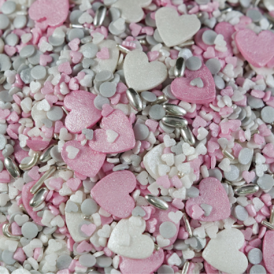 Confeitos para bolos em formas variadas de coração, círculos e amêndoas em tons rosa, branco, cinza e prateado.