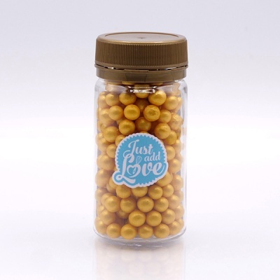 Frasco transparente com pérolas douradas e etiqueta azul com texto branco.