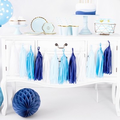 Decoração de festa com móvel branco, franjas azuis e brancas, bolas de papel azuis, balões azuis com bolinhas brancas, copos e pratos descartáveis azuis e brancos, bolo branco, presentes embrulhados azuis e brancos