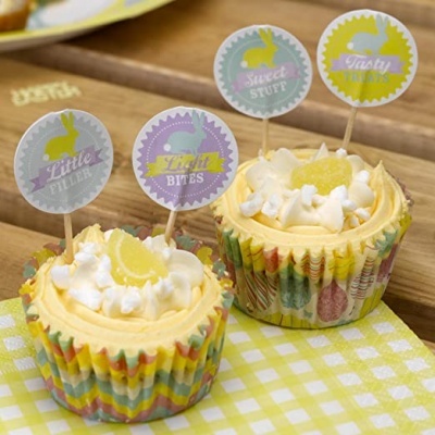 Dois cupcakes decorados com toppers de papel coloridos em pano xadrez amarelo e branco.