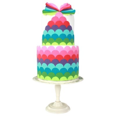 Bolo de dois andares com padrão de escamas coloridas em prato branco com pedestal