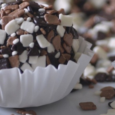 Brigadeiro com confeitos quadrados coloridos numa forminha branca