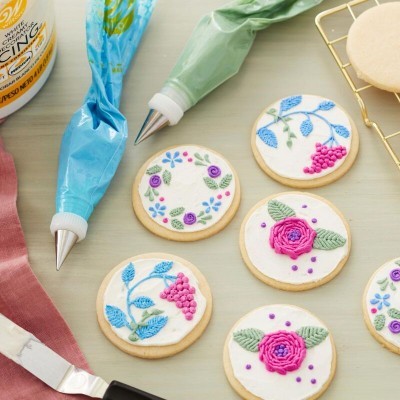 Bolachas decoradas com glacé real floral e bisnagas de glacé azul e verde com bico metálico