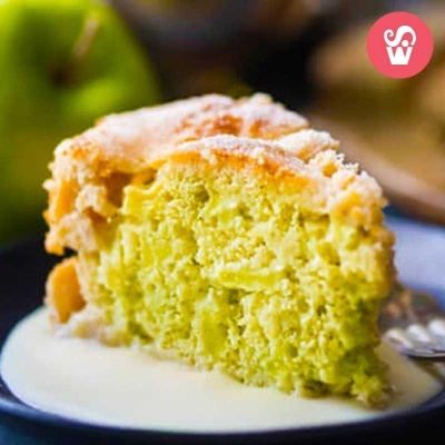 Fatias de bolo verde com cobertura crocante e açúcar em pó num prato azul com creme