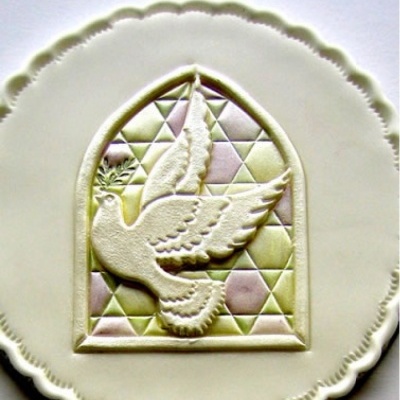 Prato branco com relevo de pomba e padrão geométrico colorido.