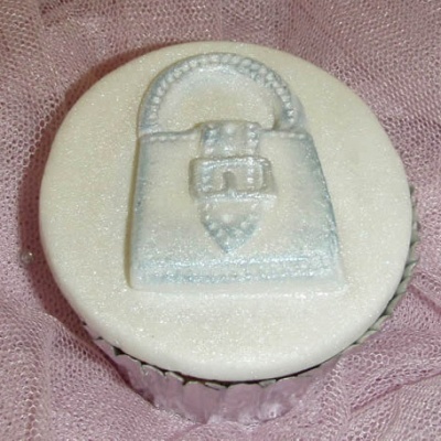 Cupcake com decoração de saco de mão prateado sobre cobertura branca