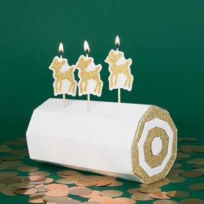 Vela branca decorativa com três renas douradas acesas e detalhes dourados em fundo verde