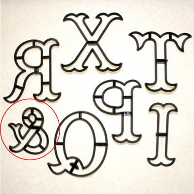 Formas de metal pretas para molde de letras com design ornamental sobre fundo claro