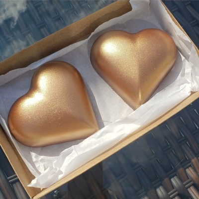 Duas caixas de coração douradas brilhantes em caixa de papelão sobre mesa de vidro