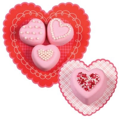 Quatro bombons rosa em forma de coração em pratos de papel corações vermelho e rosa