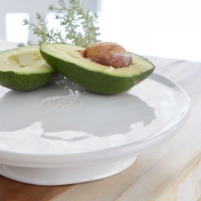 Abacate cortado ao meio numa base branca de cerâmica