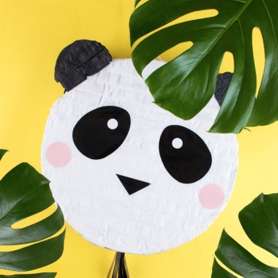 Piñata em forma de cabeça de panda com folhas verdes e fundo amarelo