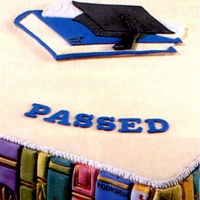 Bolo decorado com tema de livros, capelo e a palavra PASSED no topo