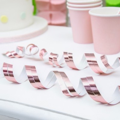 Serpentinas e copos cor-de-rosa numa mesa de festa com bolo