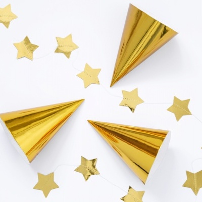 Três chapéus de festa dourados e estrelas douradas sobre fundo branco