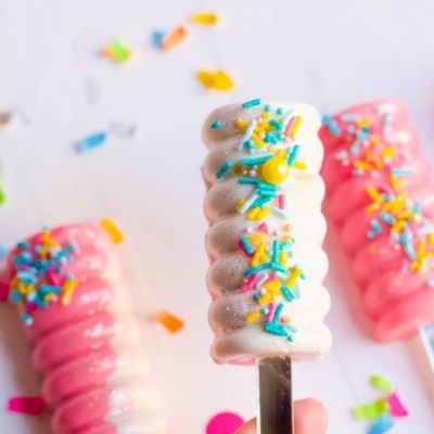 Picolés em espiral com granulados coloridos e confetes no fundo