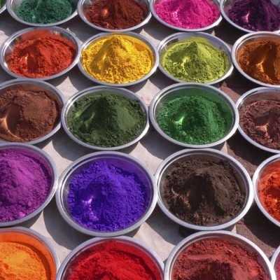 Recipientes metálicos com pós coloridos em várias cores sobre superfície branca