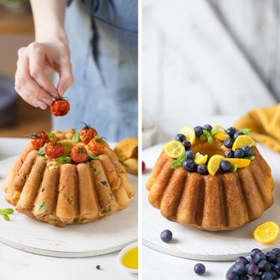 Dois bolos bundt cake decorados, um com tomates cherry e ervas, outro com limão e mirtilos