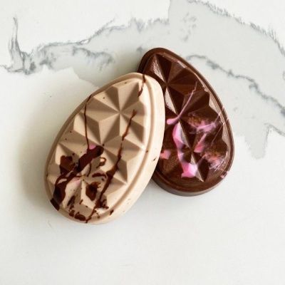 Dois ovos de chocolate decorados sobre superfície branca marmoreada