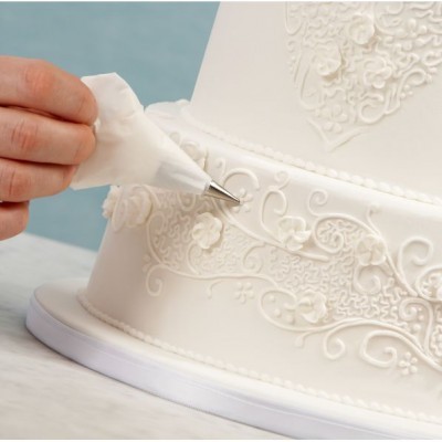 Decoração detalhada de bolo branco com saco de pasteleiro