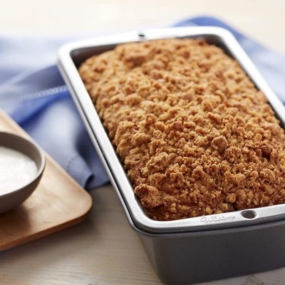 Forma de bolo metálica com bolo crumble e taça de creme ao lado