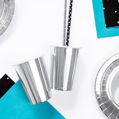 Copos e pratos prateados com guardanapos azuis e pretos com padrões de pontos