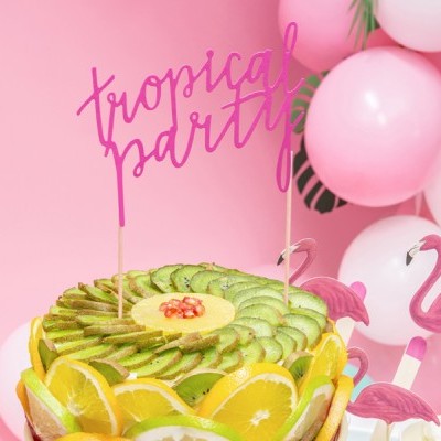 Bolo decorado com frutas e decoração tropical com texto 'tropical party'