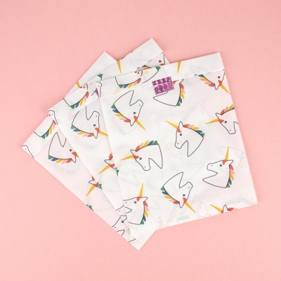 Sacos de tecido branco com padrão de unicórnios coloridos sobre fundo rosa