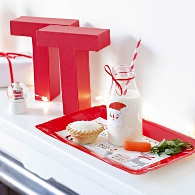 Bandeja vermelha com leite, torta, cenoura e decoração natalícia num ambiente branco