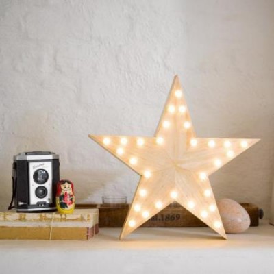 Estrela de madeira iluminada numa superfície com câmera, boneca matrioska e livros