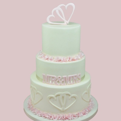 bolo de casamento de três andares verde-água com decoração de corações e texto MR & MRS