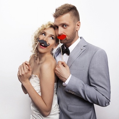 Casal vestido formalmente com acessórios divertidos sobre palitos