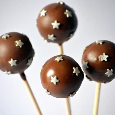 Quatro cake pops de chocolate com estrelas brancas em palitos