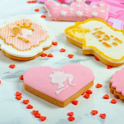 Biscoitos decorados com glacê rosa, branco, amarelo e dourado em diferentes formatos, com pequenos corações vermelhos espalhados à volta
