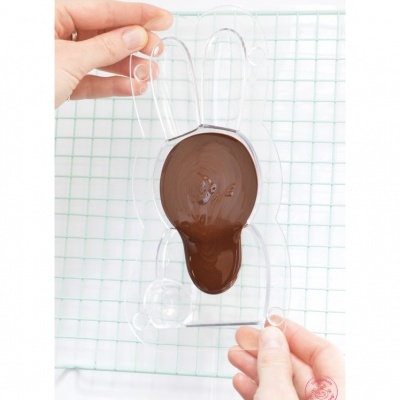 Moldes de coelho com chocolate derretido sendo segurados por mãos