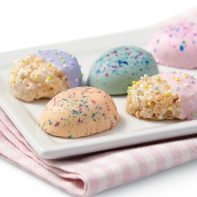 Pastéis decorativos coloridos com glacê e pequenos sprinkles num prato branco
