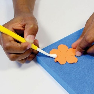 Mãos a aplicar produto em flor de papel sobre esponja azul