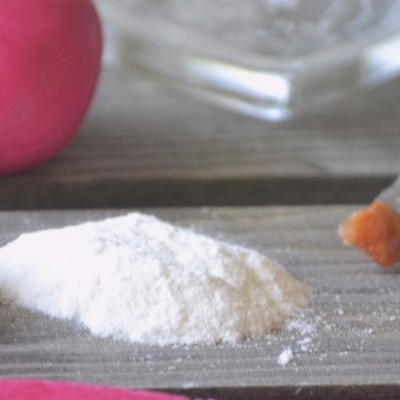 Pó branco sobre superfície de madeira com objeto vermelho e pincel ao lado