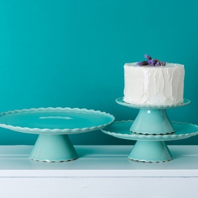 Conjunto de três pratos de cerâmica azul claro com bolo branco decorado com flores roxas