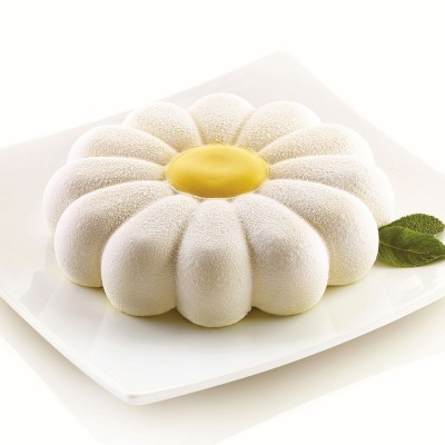 Bolo em forma de flor branca com centro amarelo num prato branco