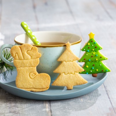 Biscoitos decorados de Natal junto a chávena de chá numa mesa de madeira cinzenta
