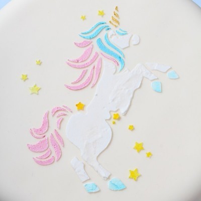 Bolo decorado com desenho de unicórnio em glacé com cores pastel e estrelas amarelas