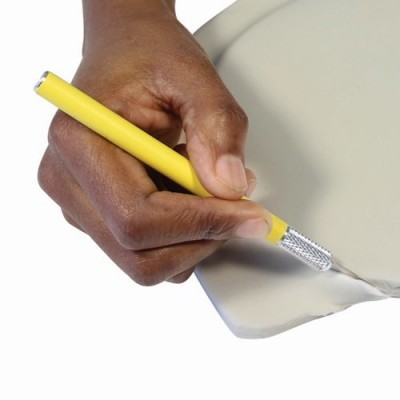 Mão a cortar placa de argila com faca de precisão de cabo amarelo