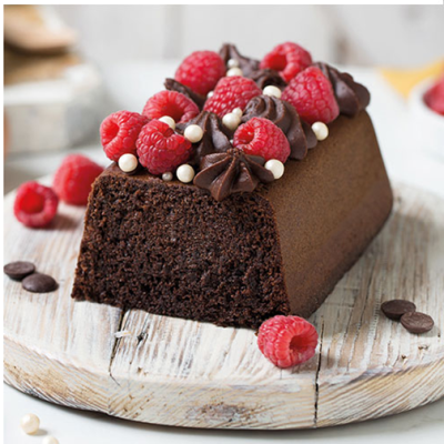 Bolo de chocolate retangular com cobertura de creme, framboesas e pérolas brancas num fundo claro