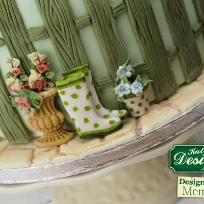 Detalhe de bolo decorado com vasos de flores e bota de borracha