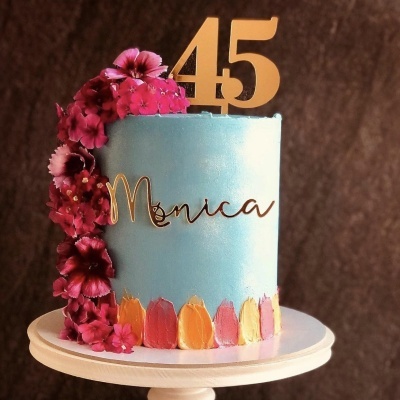 Bolo azul com flores vermelhas e número 45 dourado para aniversário.